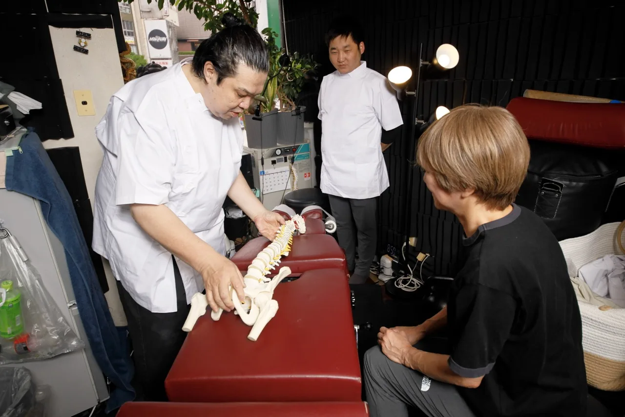 脊椎模型を使って患者に状態を説明する施術者